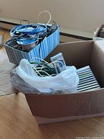 Cardboard box of CDs, cables in plastic bag, striped bin holding more CDs