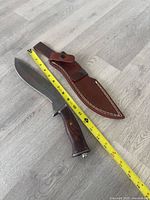 Knife and sheath beside measuring tape showing length
