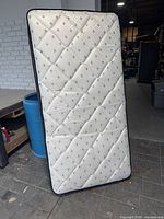 Full front view of twin pillow-top mattress standing upright showing quilt pattern