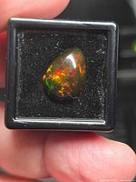 Front view of opal in display box highlighting colour play