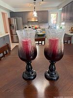 Pair of crackle glass hurricane candle holders with red candles on dining table