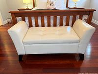Front view of white faux leather storage bench placed at foot of bed