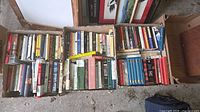 Three open cartons filled with mixed hardcover and paperback books showing overall quantity and variety