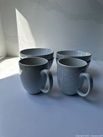 Two light-gray speckled mugs and four matching bowls