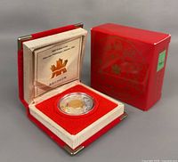 Coin in opened red clamshell case with certificate insert and outer box