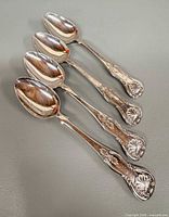 Four ornate silver teaspoons full view