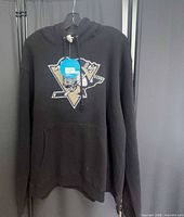 Front view of black Pittsburgh Penguins hoodie showing logo and tag