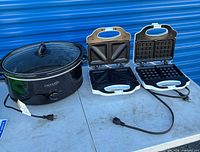 Slow cooker, sandwich maker, waffle maker on table