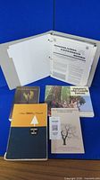 Overview of binder and four forestry books against blue backdrop