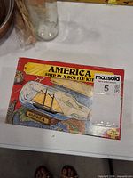 Front of red cardboard box showing 'America Ship in a Bottle Kit' graphics