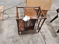 Angled view of wood side table showing two tiers and faux-bamboo spindle construction