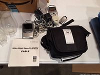 Lot overview showing HDMI cable box, handheld device, cables, black carrying case