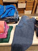 Stacked denim jeans, blue athletic shorts, folded shirts visible on table