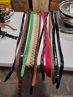Assorted belts laid out flat displaying variety of colors, materials and buckle styles