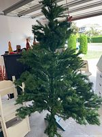 Full view of assembled green artificial Christmas tree in garage on stand