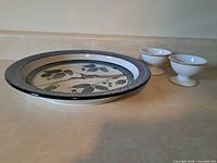 Plate with botanical design and two pedestal bowls displayed