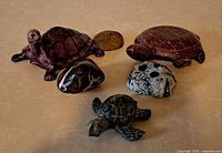 Group view of three stone turtle figurines and three polished stones