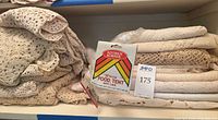 Stacks of folded crochet lace linens and packaged Kitchen Korner nylon food tent