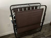 Folded metal rollaway twin bed showing frame, spring deck, support fabric and mattress edges