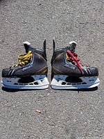 Both Bauer Supreme youth skates side by side showing mismatched laces and overall wear
