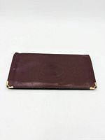 Front exterior showing burgundy leather, embossed logo, gold-tone corners