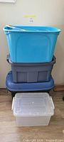 Stacked four plastic totes in blue, dark gray, dark blue, clear