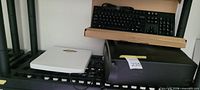 Overview showing keyboard in open carton, white scale, black printer-shredder, cables