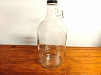 Full view of clear glass growler jug standing on wooden surface