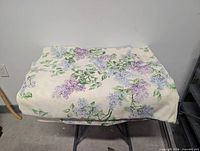 Full view of folded floral tablecloth on small table