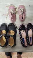 All three pairs of girls shoes arranged on surface