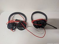 Both headsets coiled with red cables visible, boom mics folded