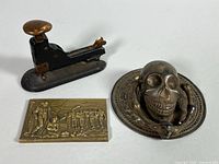 All three items: skull door knocker, brass plaque, Hotchkiss stapler