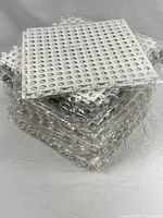 Stack of shrink-wrapped white and gray perforated vinyl squares