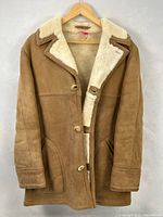 Front view of suede shearling coat on hanger