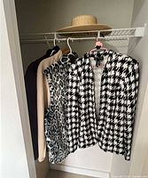 Blazer, vest, tan jacket and straw hat hanging in closet
