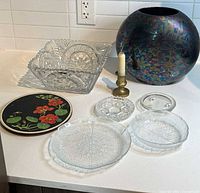 All items arranged on countertop: vase, square dish, candlestick, trivet, two leaf plates, two small clear dishes
