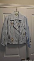 Full front view of light blue faux leather moto jacket on hanger