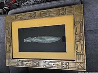 Front view of framed shadow box displaying carved mask and decorative frame