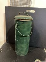 Full view of green cylindrical container with lid and handle