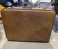 Front exterior of tan hard-sided suitcase