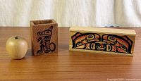 Tall open cedar box with wolf design, wood apple for scale, sliding-lid salmon box