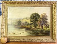 Frontal view of signed landscape painting in ornate gilt wood frame