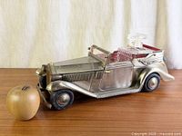 side view of metal car with decanter and glasses, apple for scale