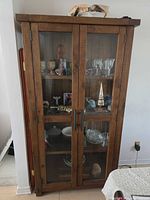 full view of cabinet front showing glass doors, metal handles, shelves and finish