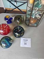 Five glass paperweights and glass cabinet grouped on table