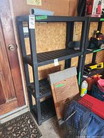 Full view of black plastic shelving unit with four ventilated shelves
