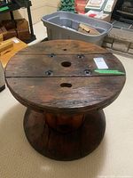 Oblique view of entire wooden spool side table showing round top, base and wood finish