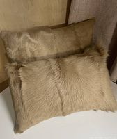 Two tan goat fur pillows stacked