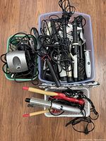 Three bins of assorted corded curling irons, hot brush, clipper