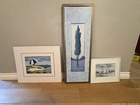 Set of three framed art pieces leaning against wall